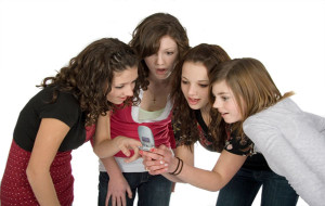 four teen girls looking at cell phone